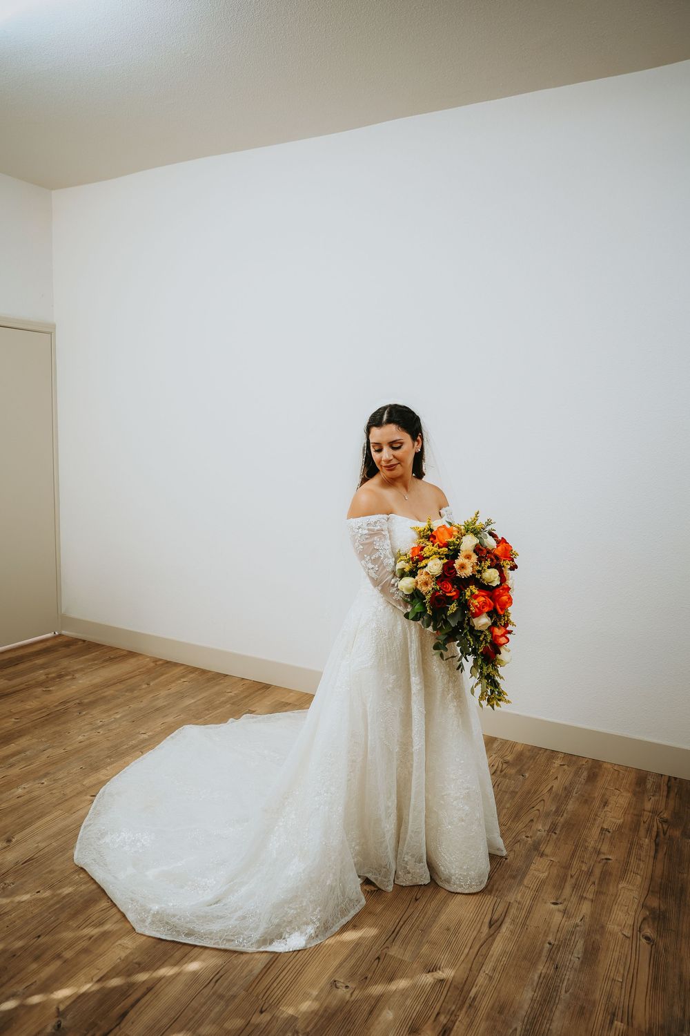 A wedding dress with lace details and flowing train photographed in sequence against white walls and wooden floors.