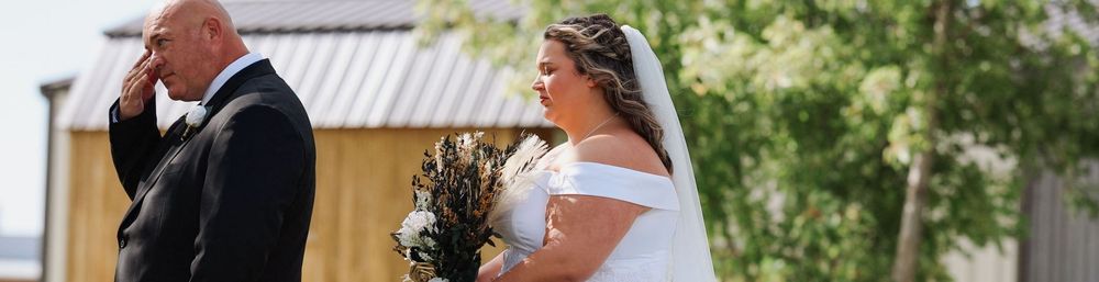 A couple shares an emotional moment during their outdoor wedding ceremony, with the bride holding a bouquet.