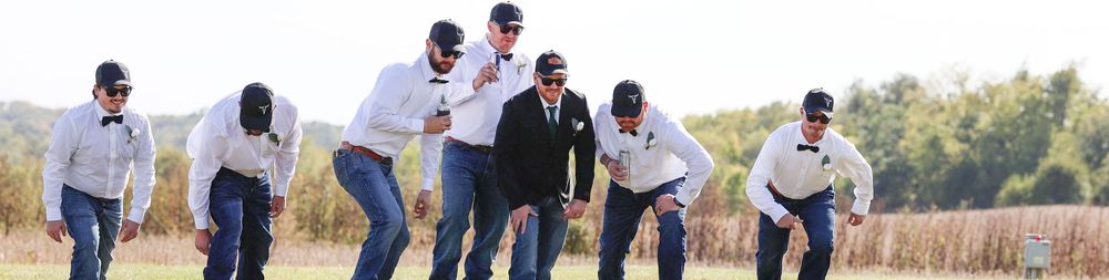 A group of people walking together in a line through an outdoor setting with tall grass and natural scenery.