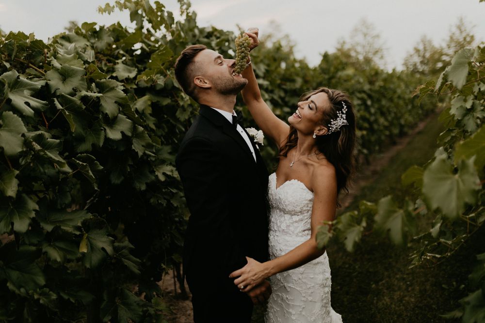 Newlyweds embracing in a lush vineyard setting at golden hour.