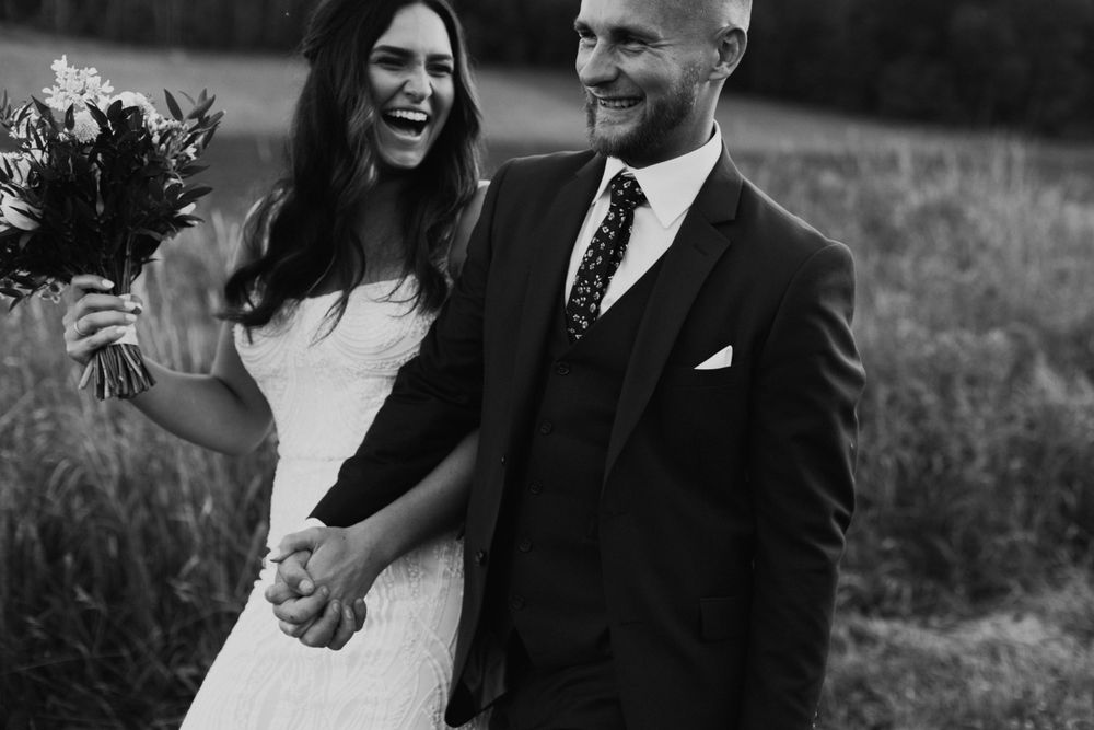 A candid black and white wedding photo capturing laughter and joy between the couple.