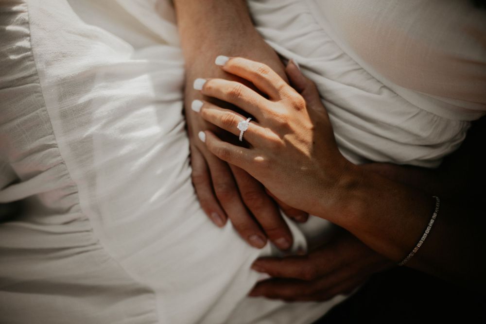 Intimate close-up of hands and white fabric in dramatic lighting.