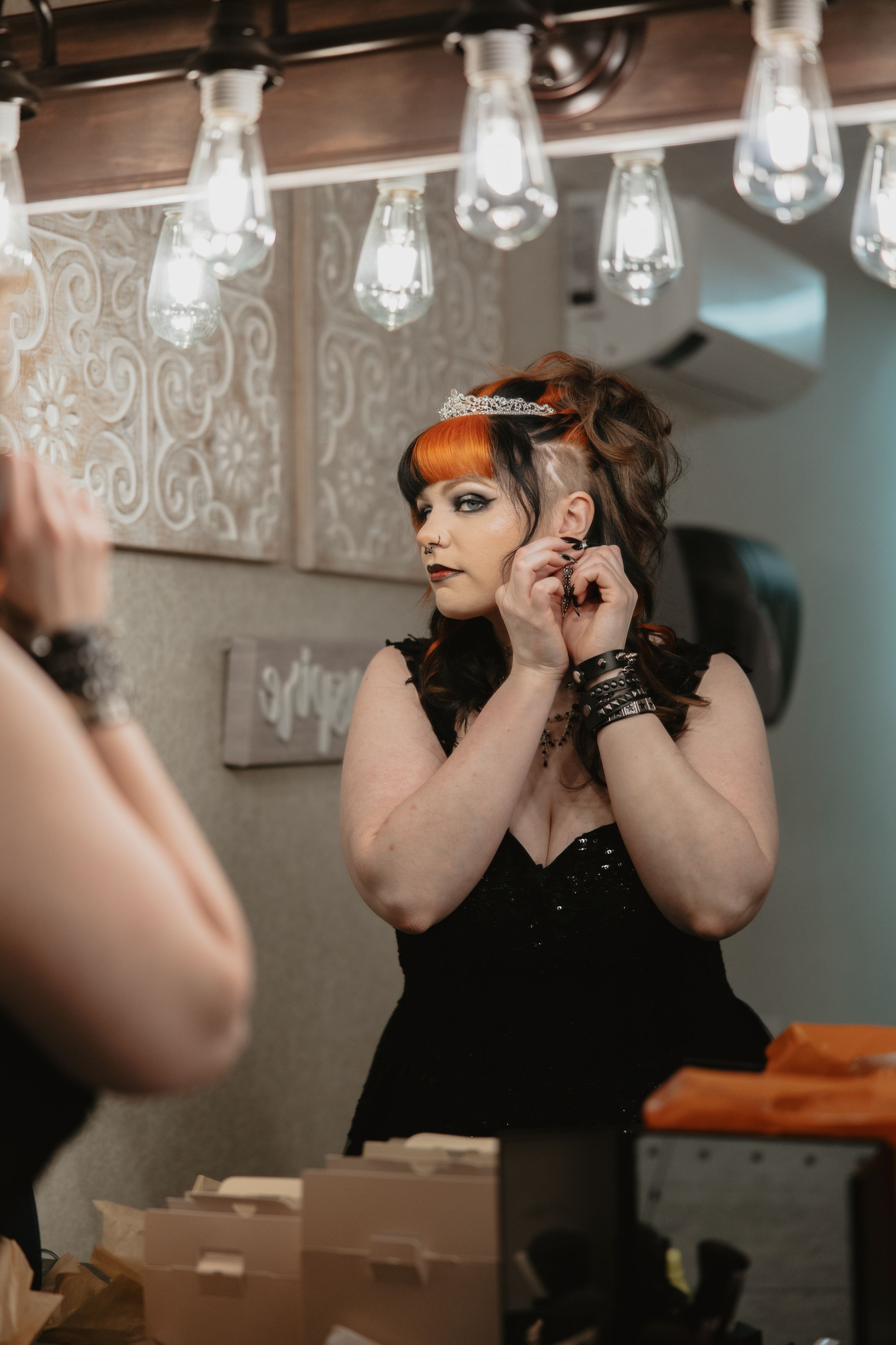 Dramatic getting ready shots in dressing room with hanging lights and ornate wallpaper.