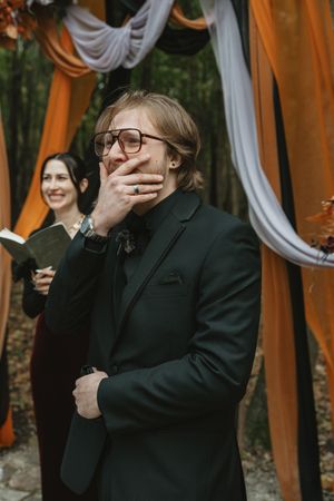 Emotional wedding ceremony reactions with orange and white fabric draped backdrop.