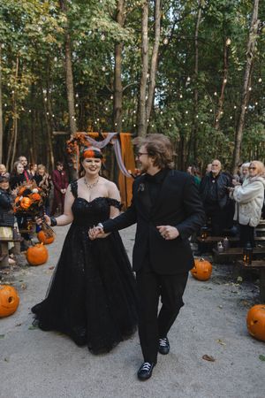 Wedding party celebrating in wooded area decorated with pumpkins and orange accents.