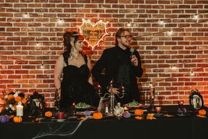 Decorative pumpkins and fall decor line a rustic brick wall with warm lighting creating a cozy autumn atmosphere.