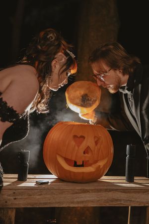 A carved jack-o'-lantern glows on a rustic wooden surface in dramatic lighting.