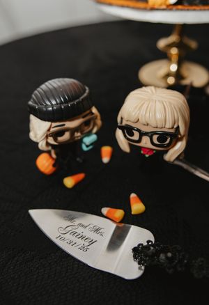 Small decorative figures and candy corn arranged with engraved knife on dark surface.