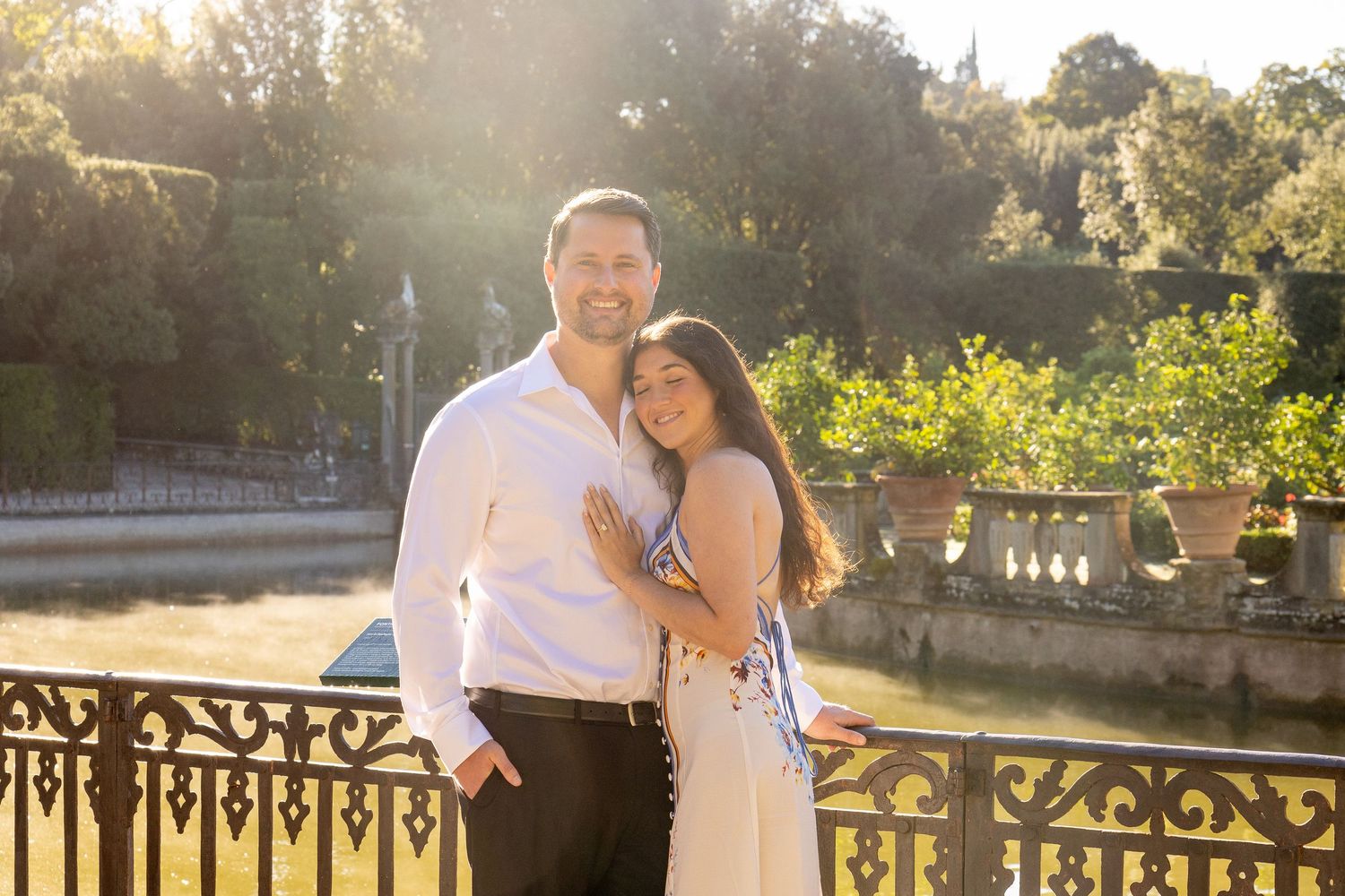 A couple shares a romantic moment during their wedding photoshoot in a scenic garden setting at sunset.