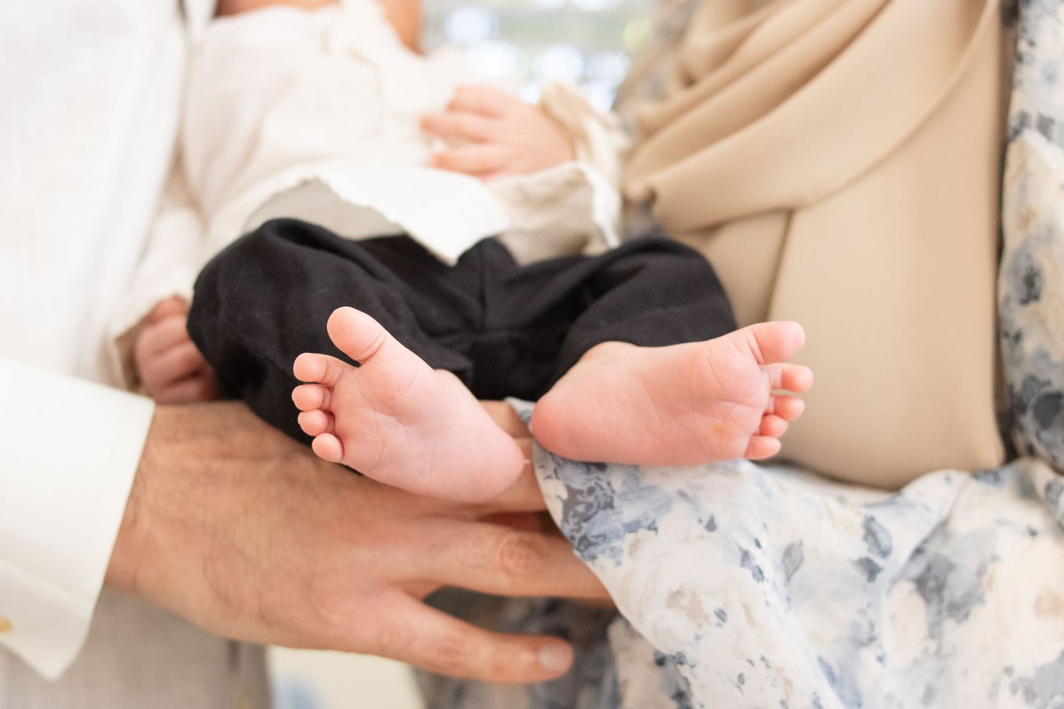 Mom and dad holding newborn baby with close up picture of baby feet