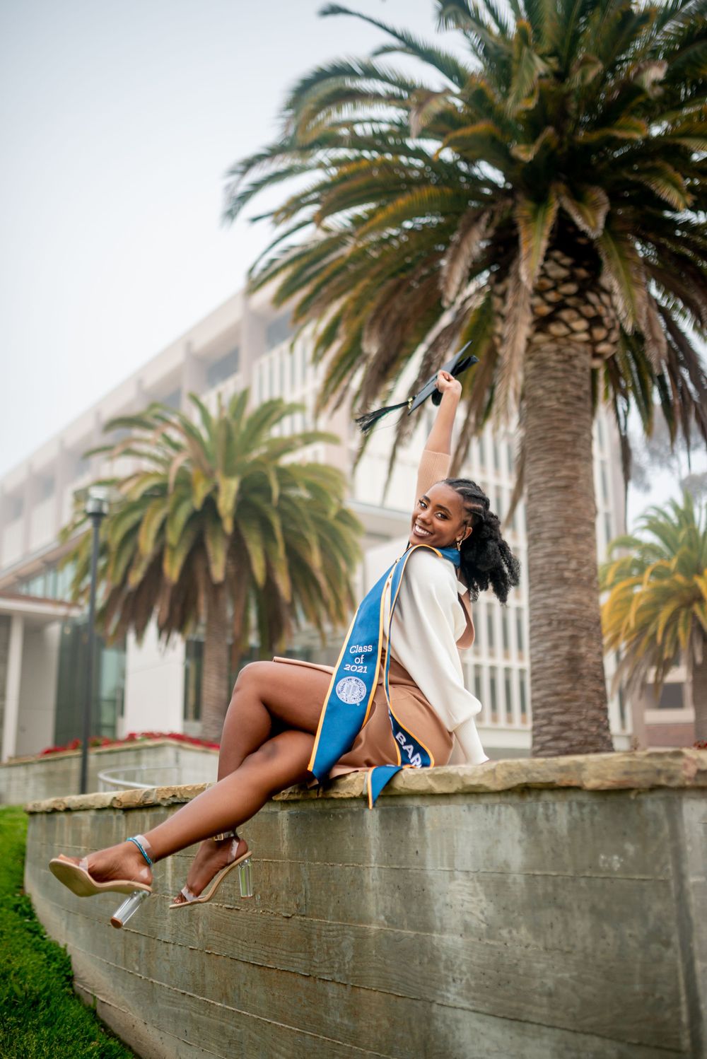 Athletic figure stretches on concrete wall with palm trees in background at sunset creating dynamic urban scene.
