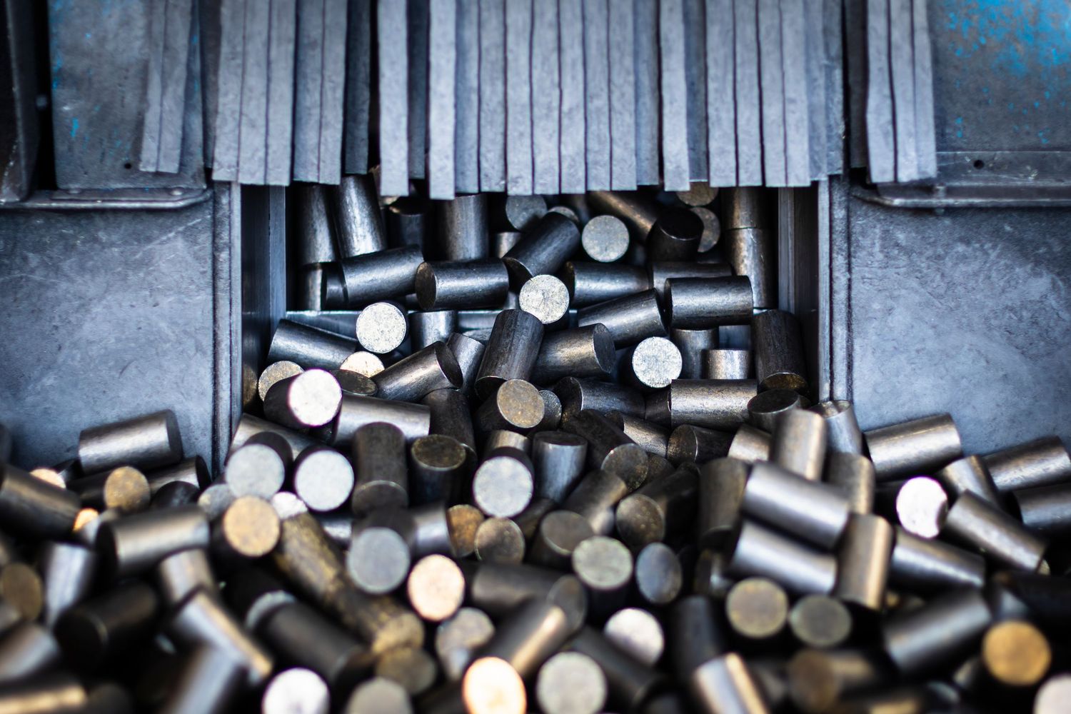 Wide angle shot of steel cylinders tumbling out of a machine into a collection trough.