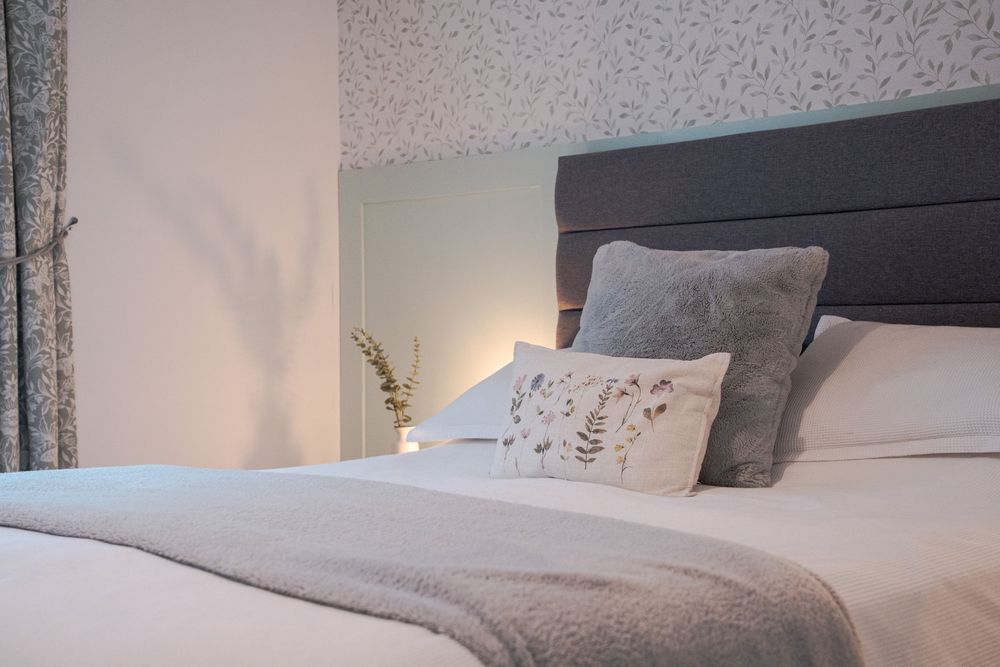 Modern bedroom interior with gray carpet, white walls, and built-in electric fireplace creating a cozy atmosphere.
