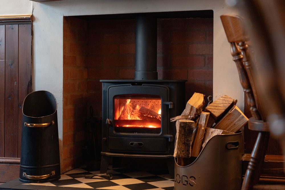 Wood burning stove and fireplace in dark rustic interior.