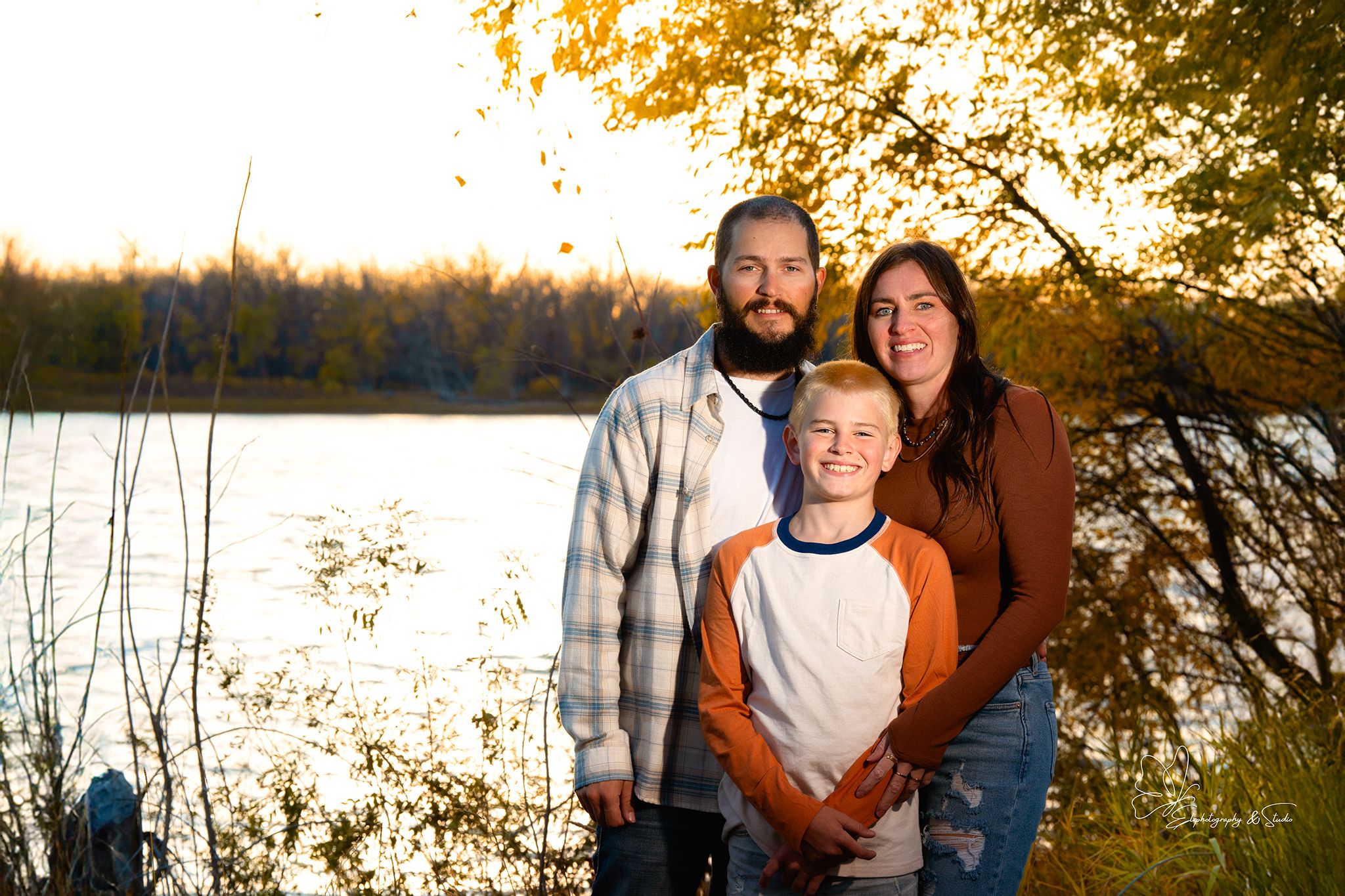Family portrait session at sunset with golden autumn trees in background in Williston, North Dakota.