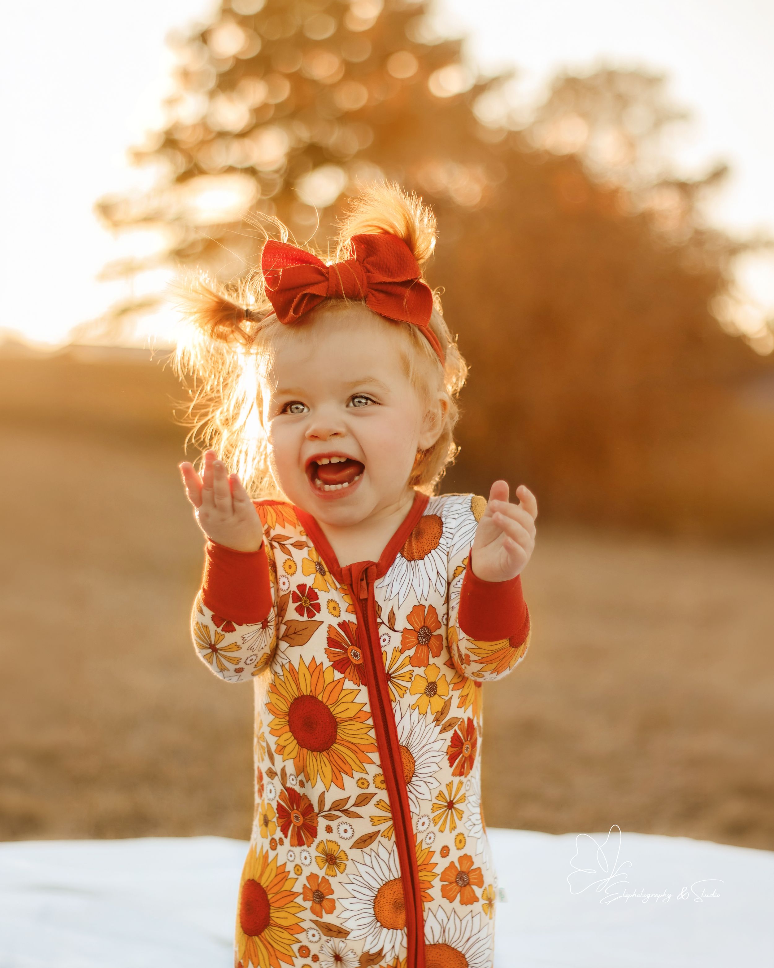 Child wearing sunflower print outfit laughing joyfully in sunset light in Williston, North Dakota.