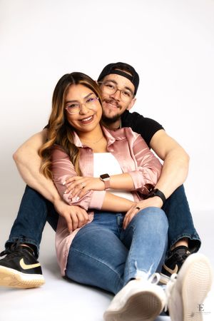 Two people sitting close together on a white studio floor in Williston, North Dakota.