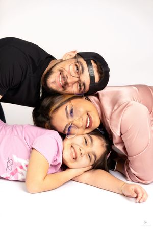 Three people stacked in a playful pose against a white background in Williston, North Dakota.