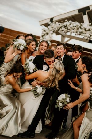 Wedding party laughs together in candid group photo.