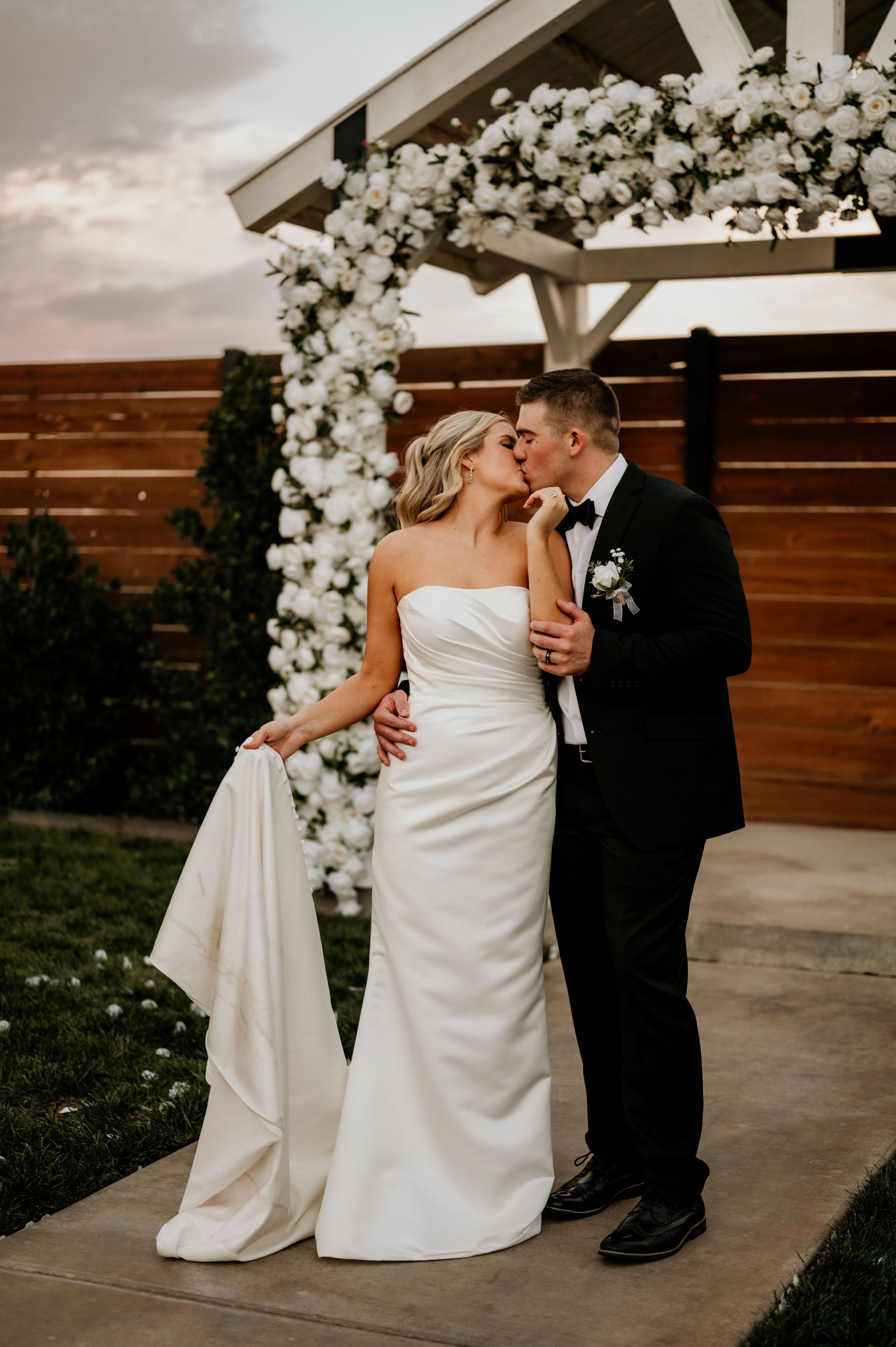 Elegant wedding ceremony setup with white floral arch and romantic lighting.