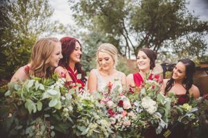 Bridesmaids hold elegant floral bouquets while posing outdoors.