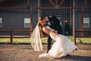Wedding couple and party taking fun photos in front of a rustic barn.