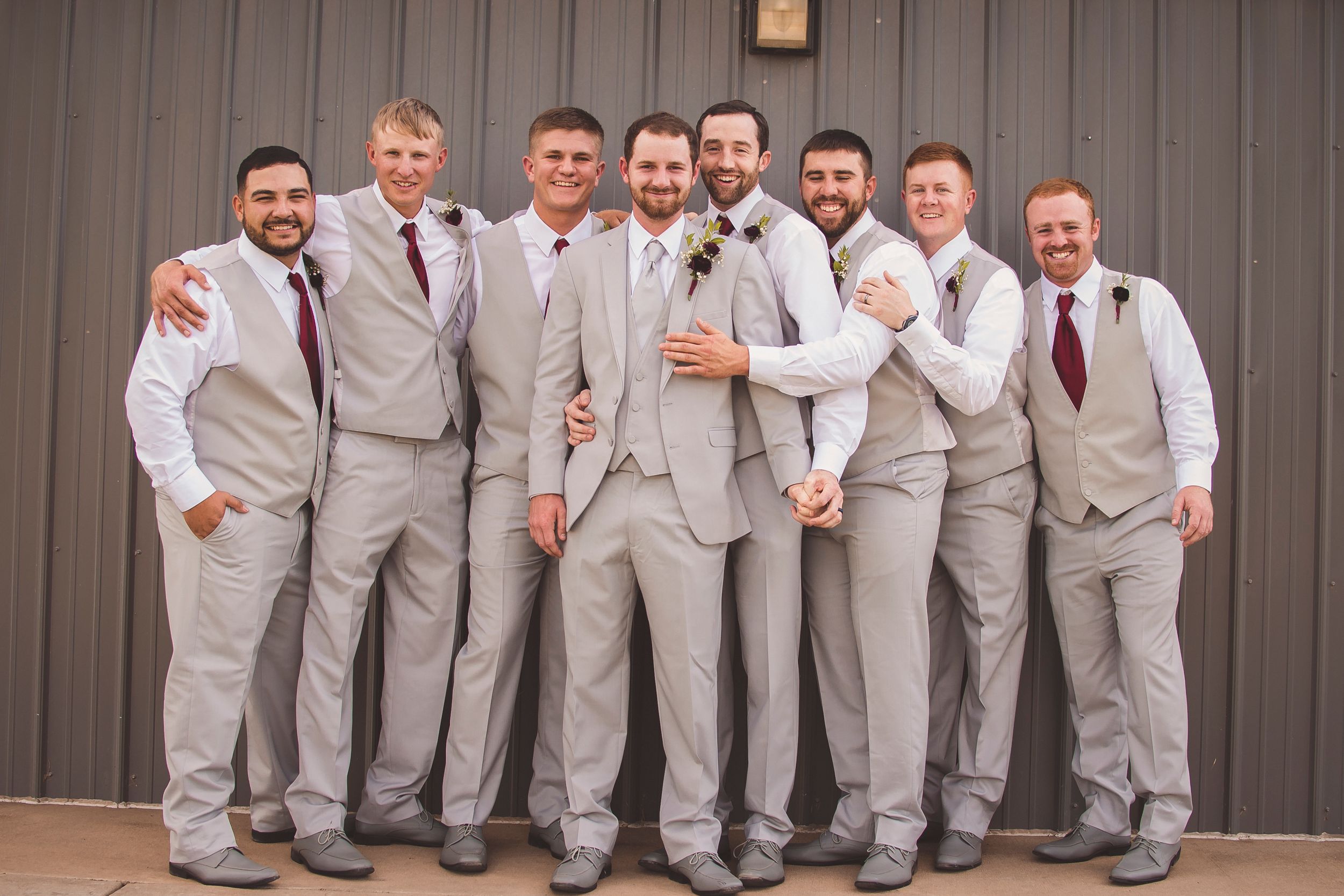 Groomsmen in light gray suits pose together for formal wedding photo.