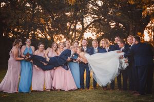 Wedding party poses for sunset photos with bridesmaids in pastel dresses and groomsmen in dark suits.