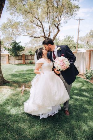 Romantic wedding couple dancing and twirling on a grassy lawn during their outdoor celebration.
