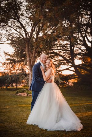 Couple shares intimate moment under autumn trees during golden hour wedding photos.