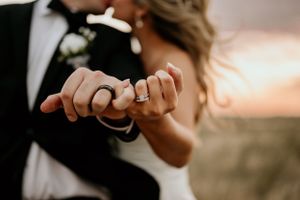 Close-up details of wedding rings and hands during romantic moment.
