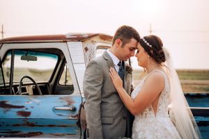 Romantic wedding portraits taken near vintage blue car at sunset.