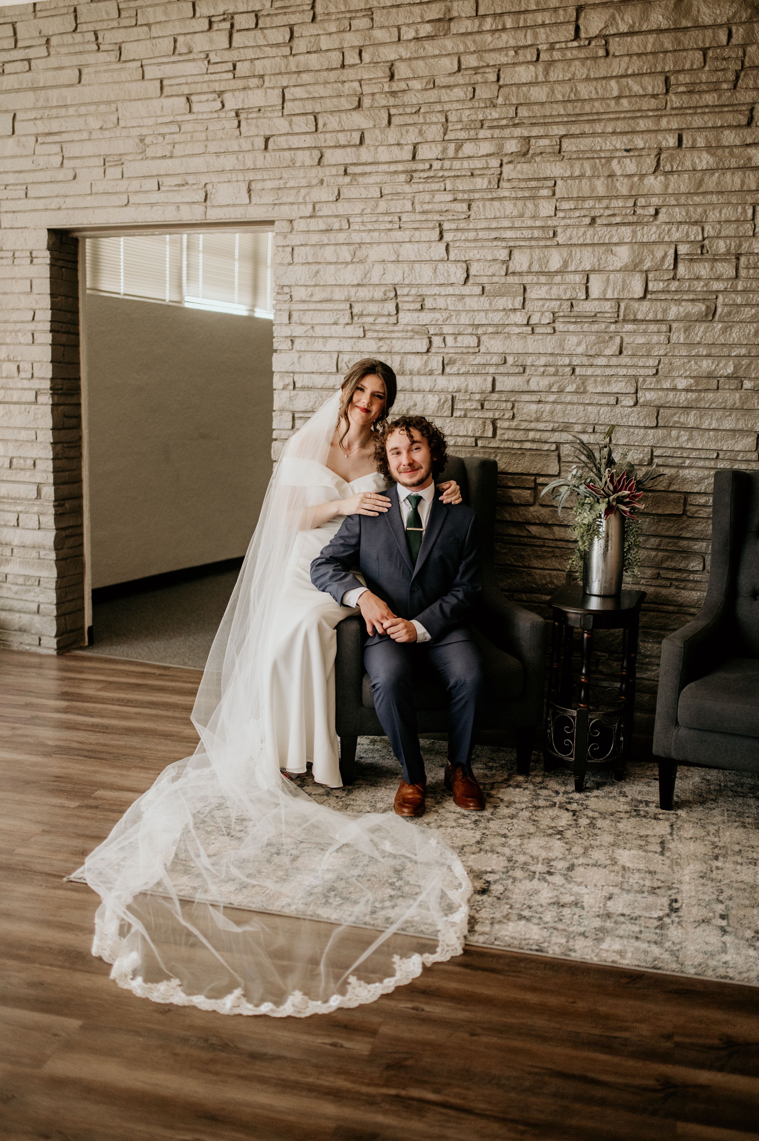 Indoor wedding portraits against modern stone wall with hardwood floors.