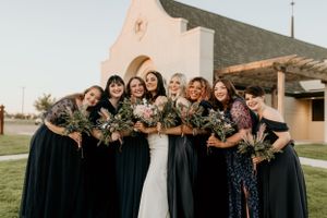 Bridesmaids in navy dresses pose together holding bouquets outdoors.