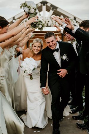 Wedding party forms tunnel arch for celebration exit.