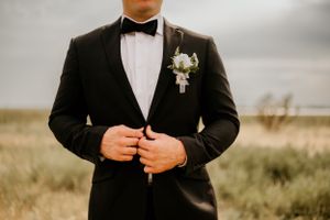 Detail shots of groom in classic black tuxedo and bow tie on wedding day.