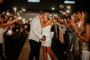 Wedding sparkler exit with guests creating tunnel of lights at night.