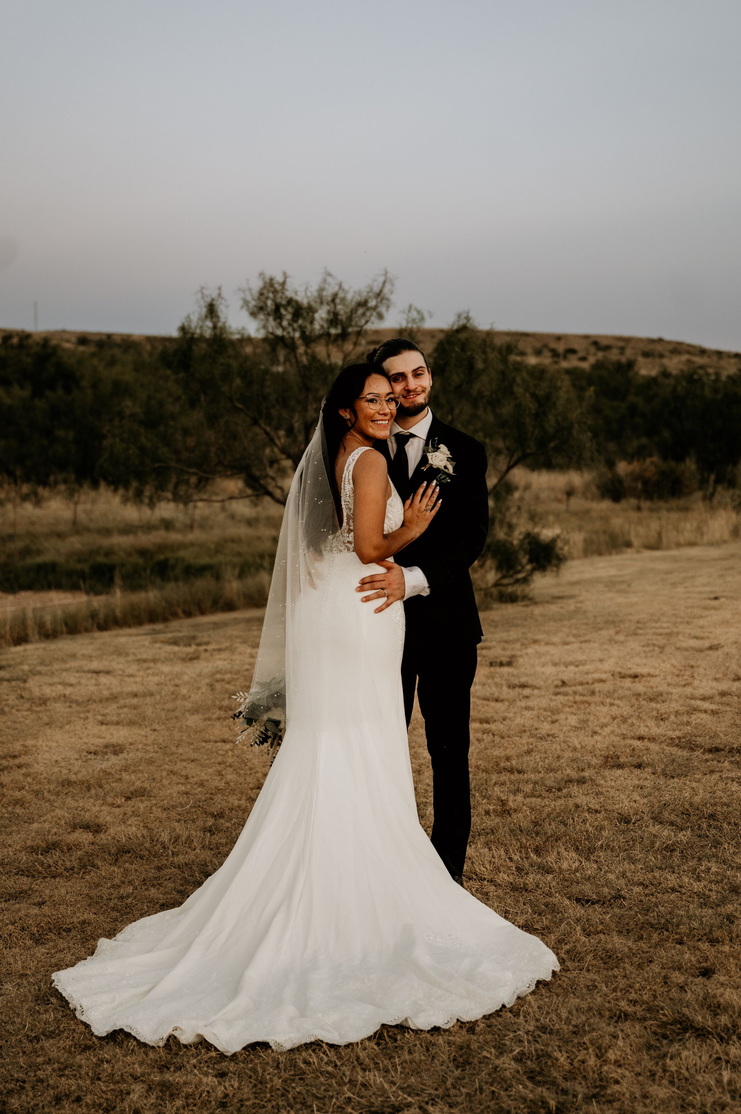 Desert wedding portraits with flowing white dress against natural landscape.