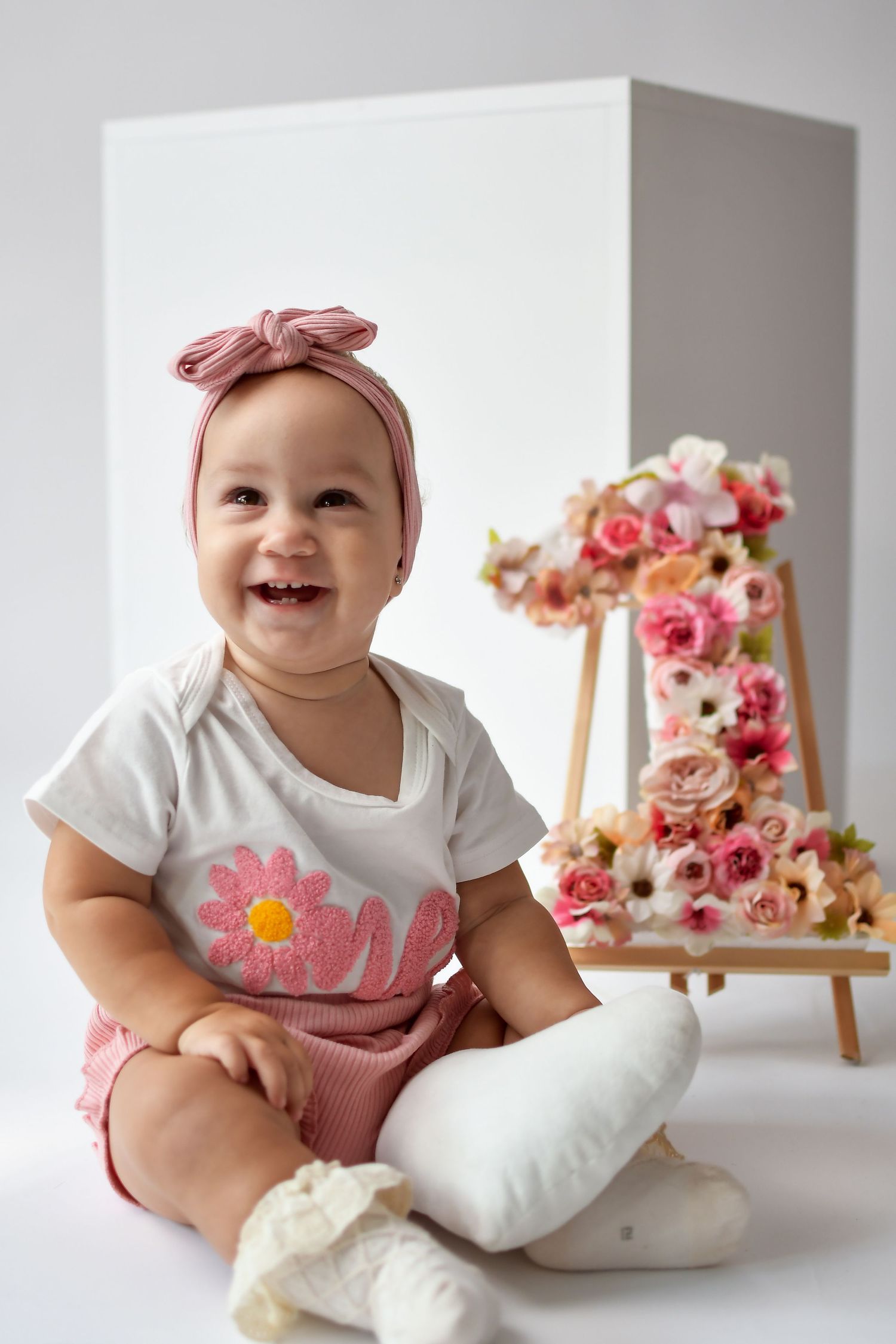 A person in a pink dress celebrates with confetti and balloons during a festive birthday photoshoot.