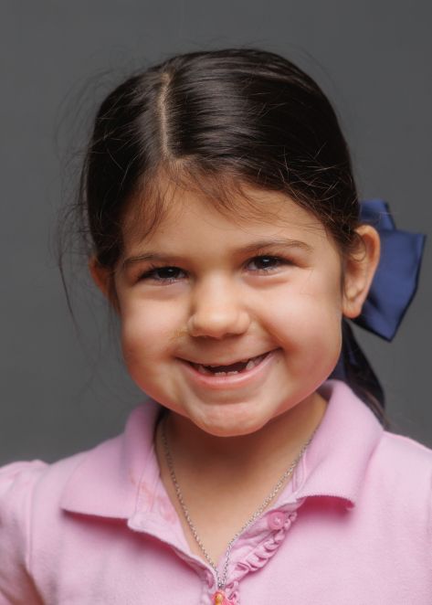 A child wearing a pink collared shirt smiles brightly in a series of four similar portrait photos.