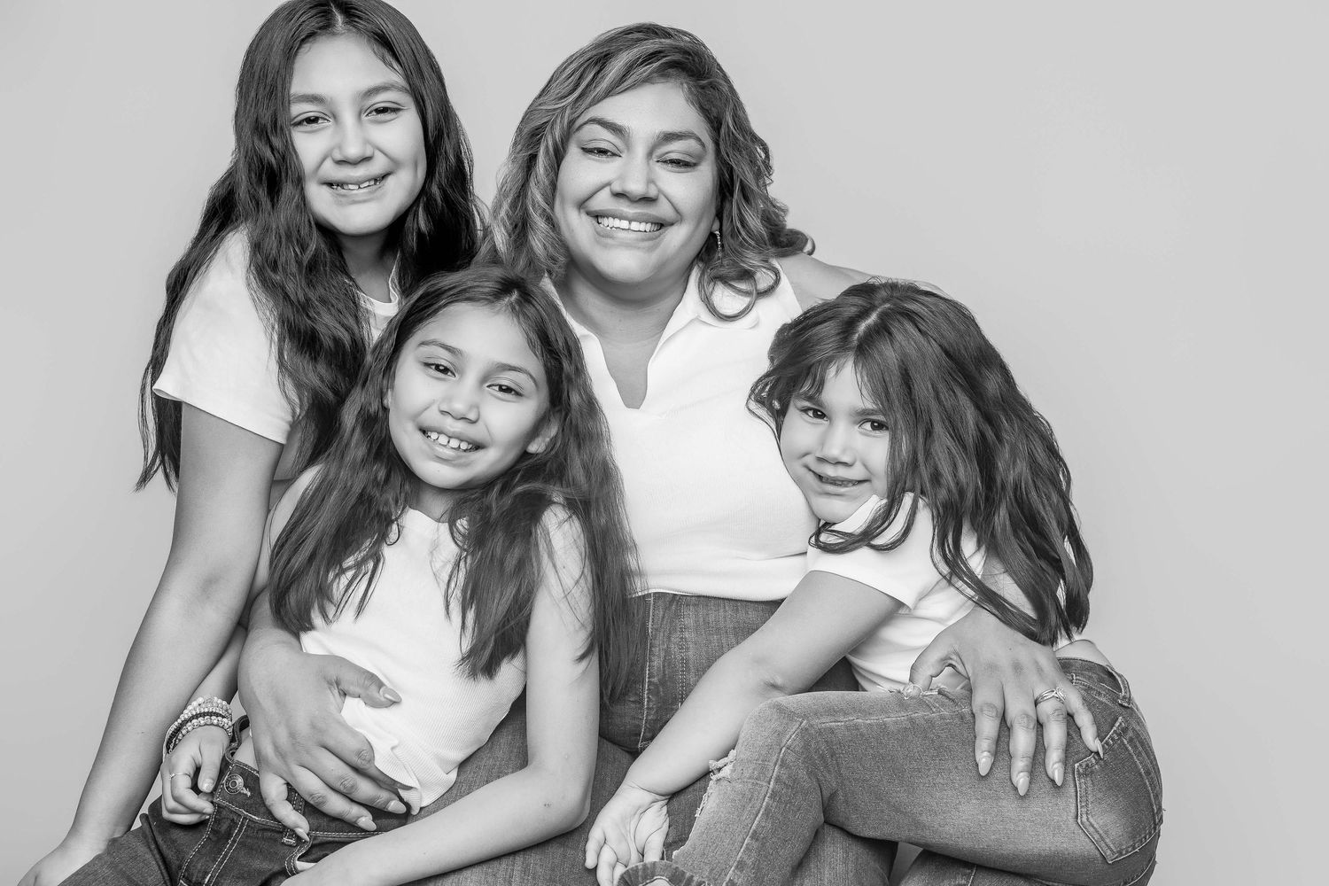 Family snuggling together on a cozy gray couch in a bright room with children's books on the wall.