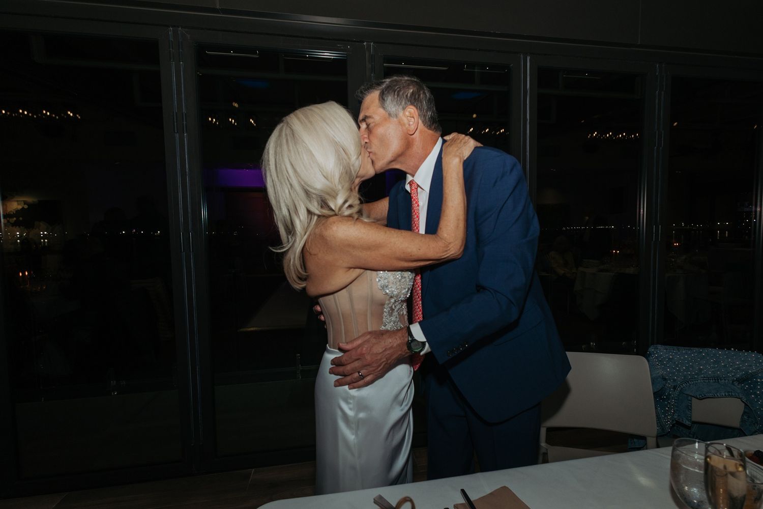A couple shares a romantic dance together in a dimly lit venue during a wedding reception celebration.
