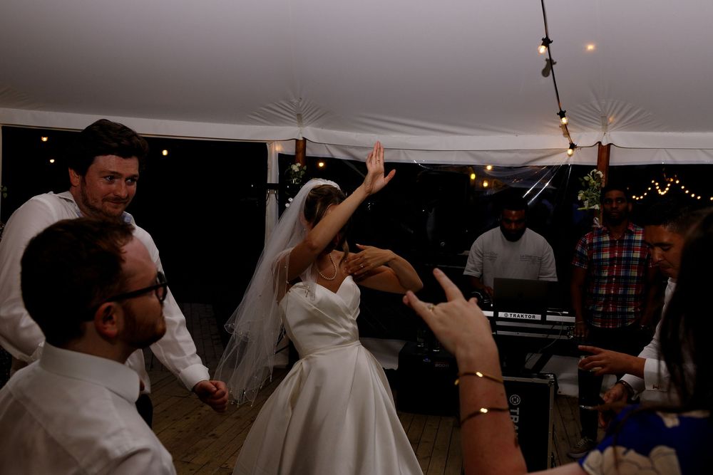 Wedding guests dancing and celebrating on a dance floor at an indoor reception venue.