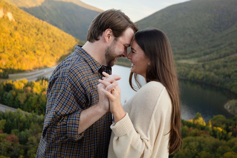 A couple shares an intimate moment in the mountains during golden hour as autumn colors paint the landscape.