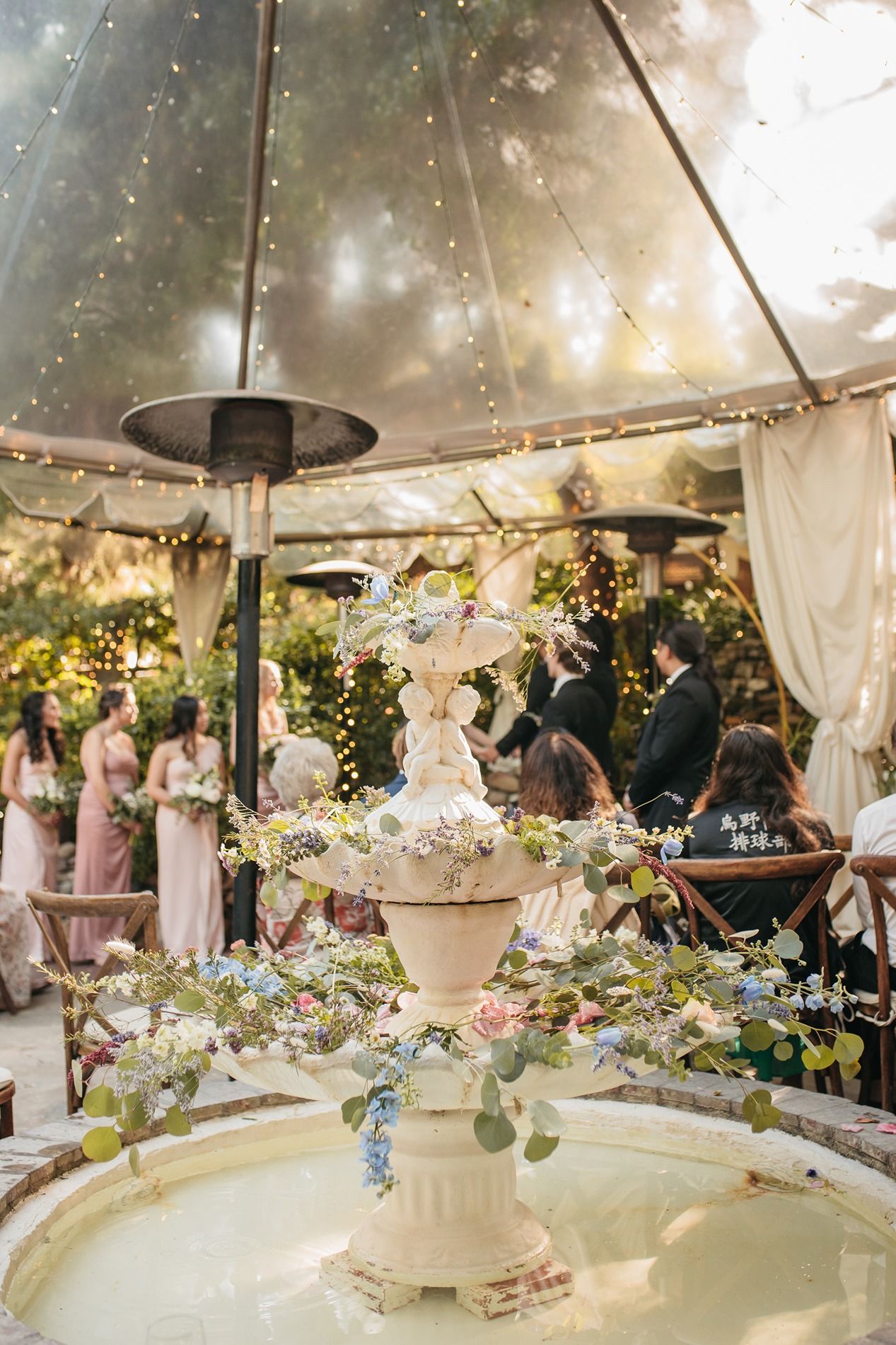 Elegant wedding ceremony setup under clear tent with floral arrangements and white draping creating a romantic atmosphere.