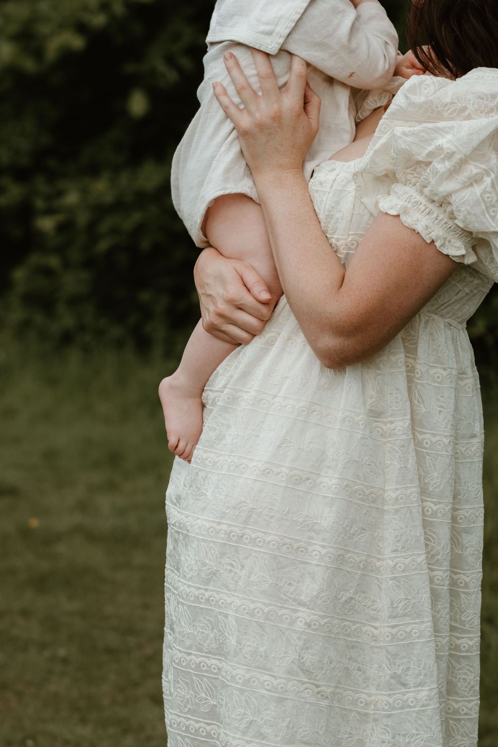 Close-up details of a delicate white lace dress against a natural outdoor background.