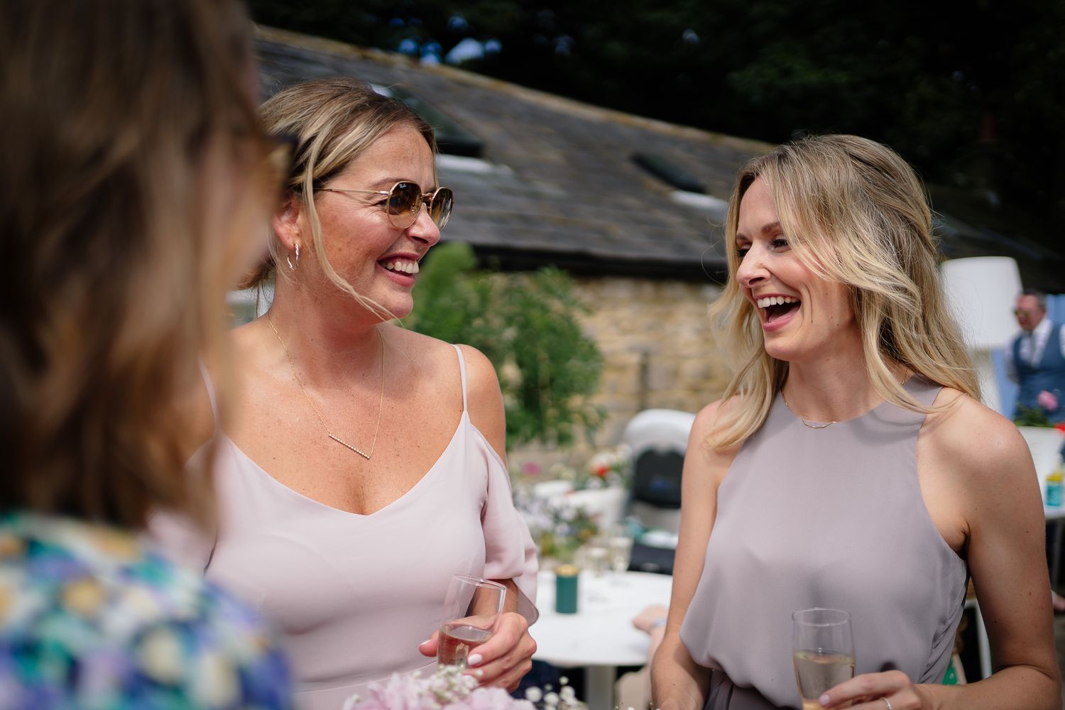 Wedding guests share joyful moments during outdoor celebration. Woodhill Hall.