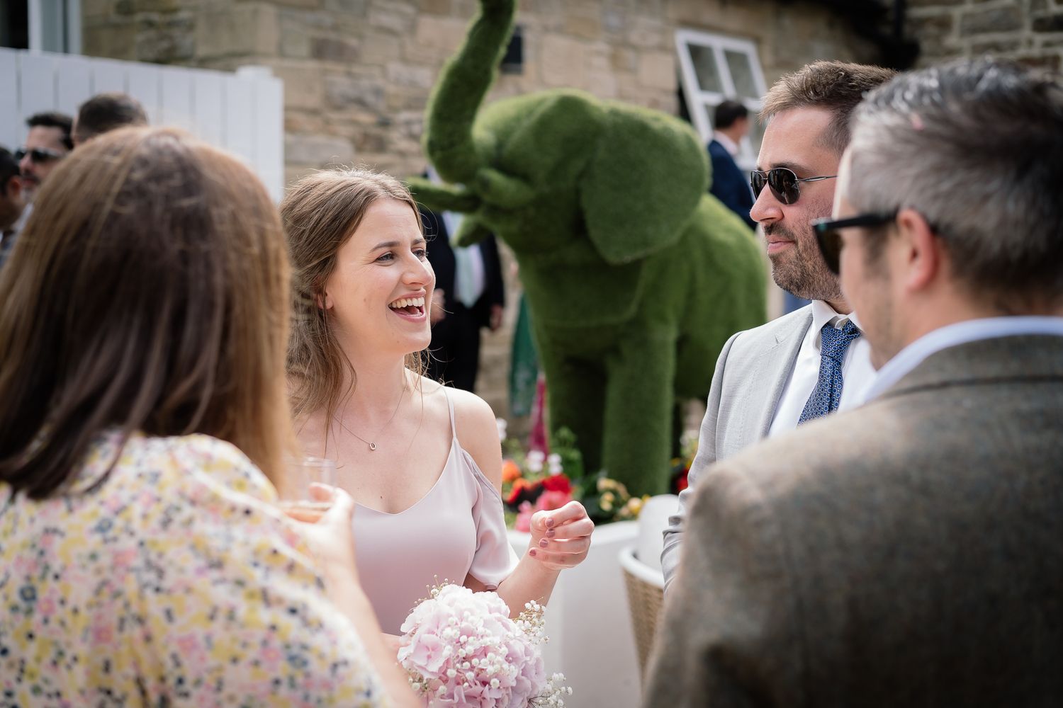 Wedding guests enjoying conversation during outdoor garden reception. Woodhill Hall.