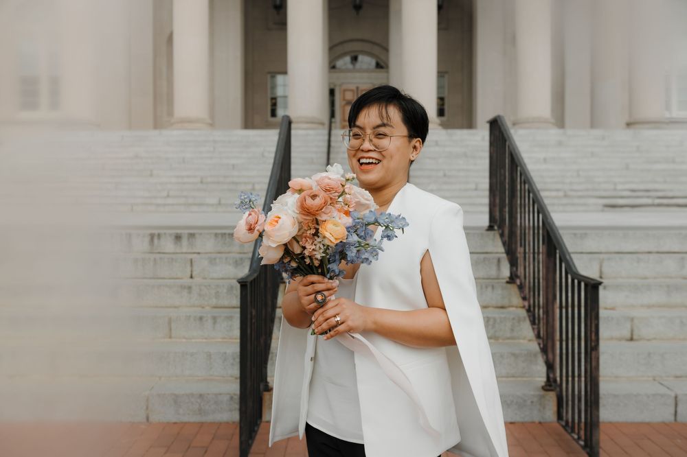 Wedding couple posing on grand stone steps of a historic building.