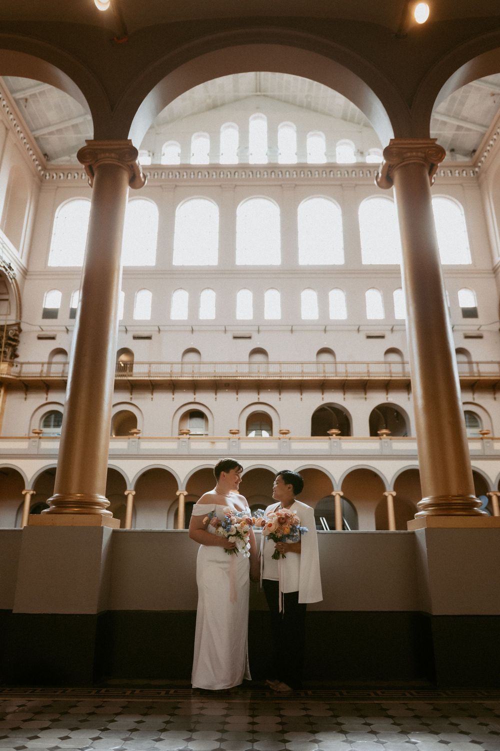 Wedding ceremony in a beautiful columned hall with arched windows and natural light.